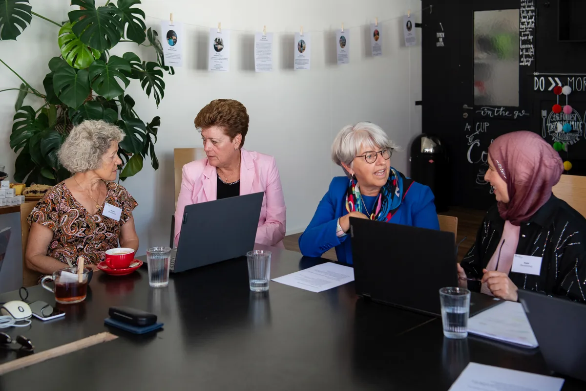 Vier Damen sitzen mit zwei Laptops an einem Tisch.